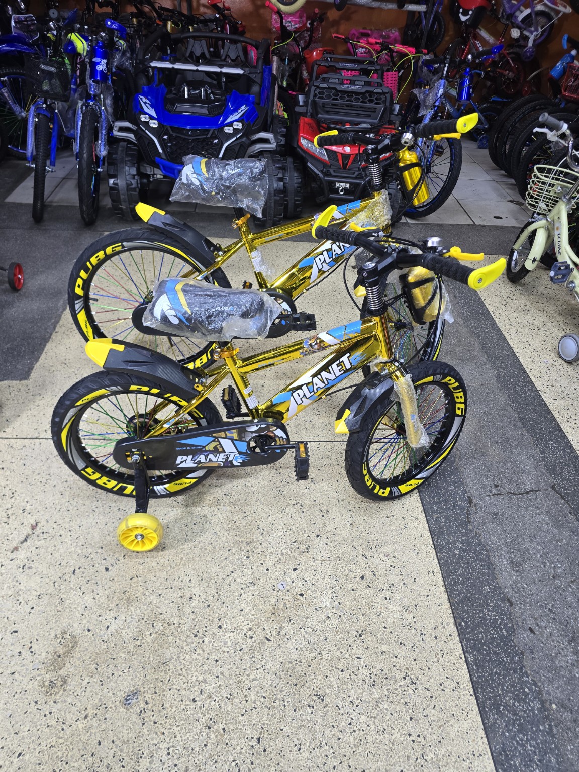 Size 16 Planet kids bicycle in metallic with accents, training wheels, chain guard, front and rear mudguards, and sporty PUBG-branded. wheel decals, d