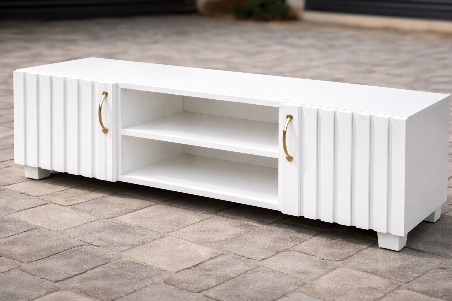 Modern white TV stand with fluted cabinet doors, gold handles, and open center shelving for media storage.