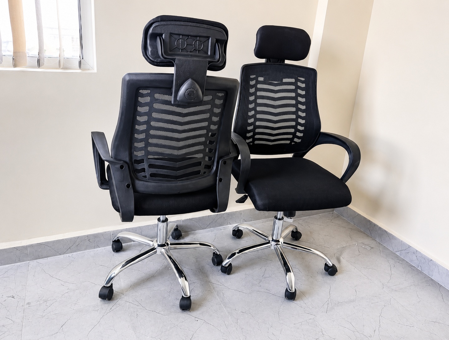 High back ergonomic black mesh office chair with adjustable headrest, padded seat, chrome base, and smooth caster wheels.