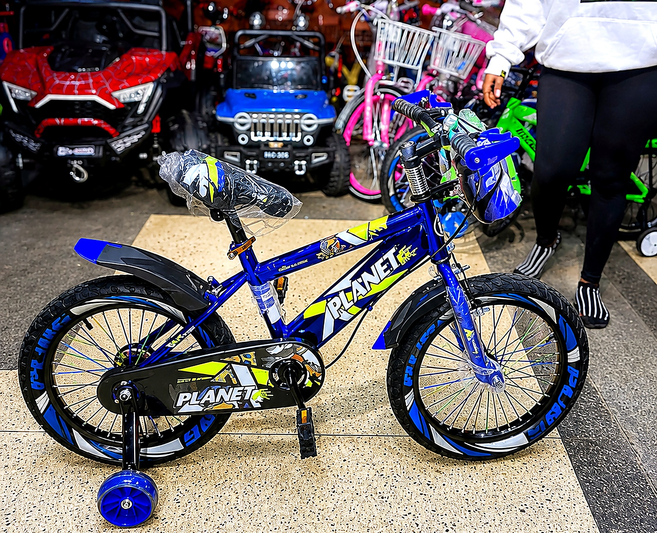 Planet 16-inch kids bicycle in blue with removable training wheels, front suspension, chain guard, mudguards, and adjustable saddle.