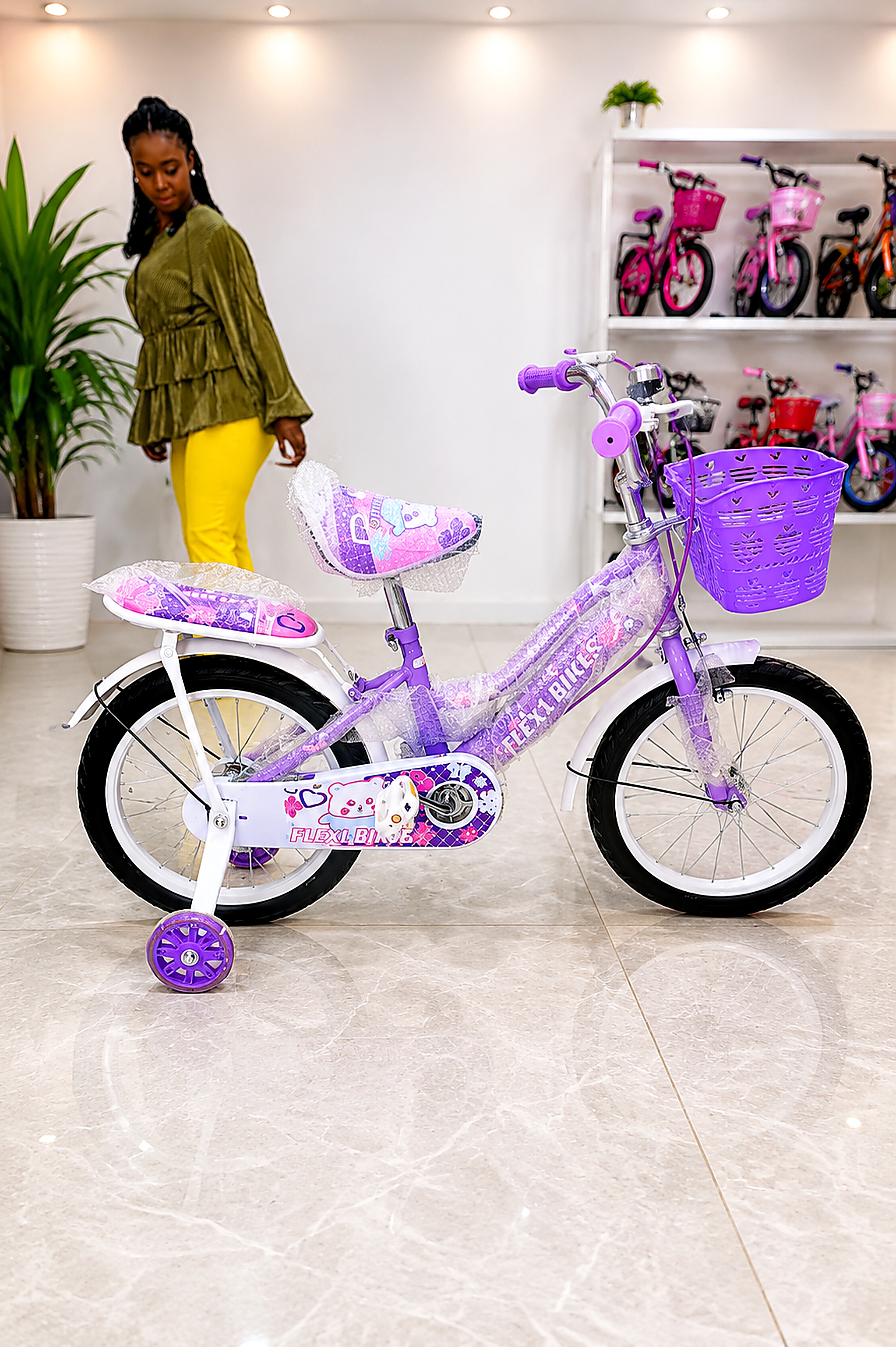 Flexi Bikes 16-inch girls bicycle in purple with training wheels, front basket, rear carrier, chain guard, mudguards, and padded saddle.