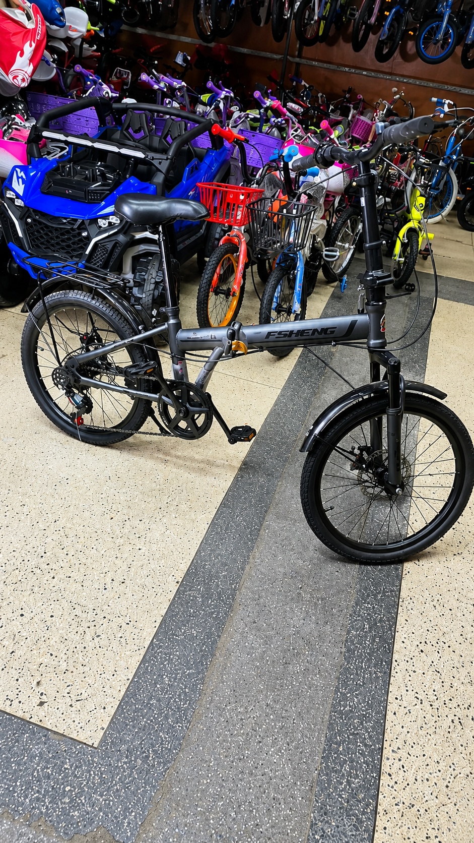 FSheng 20-inch grey foldable bicycle with front suspension, 7-speed gears, and front & rear mechanical disc brakes.