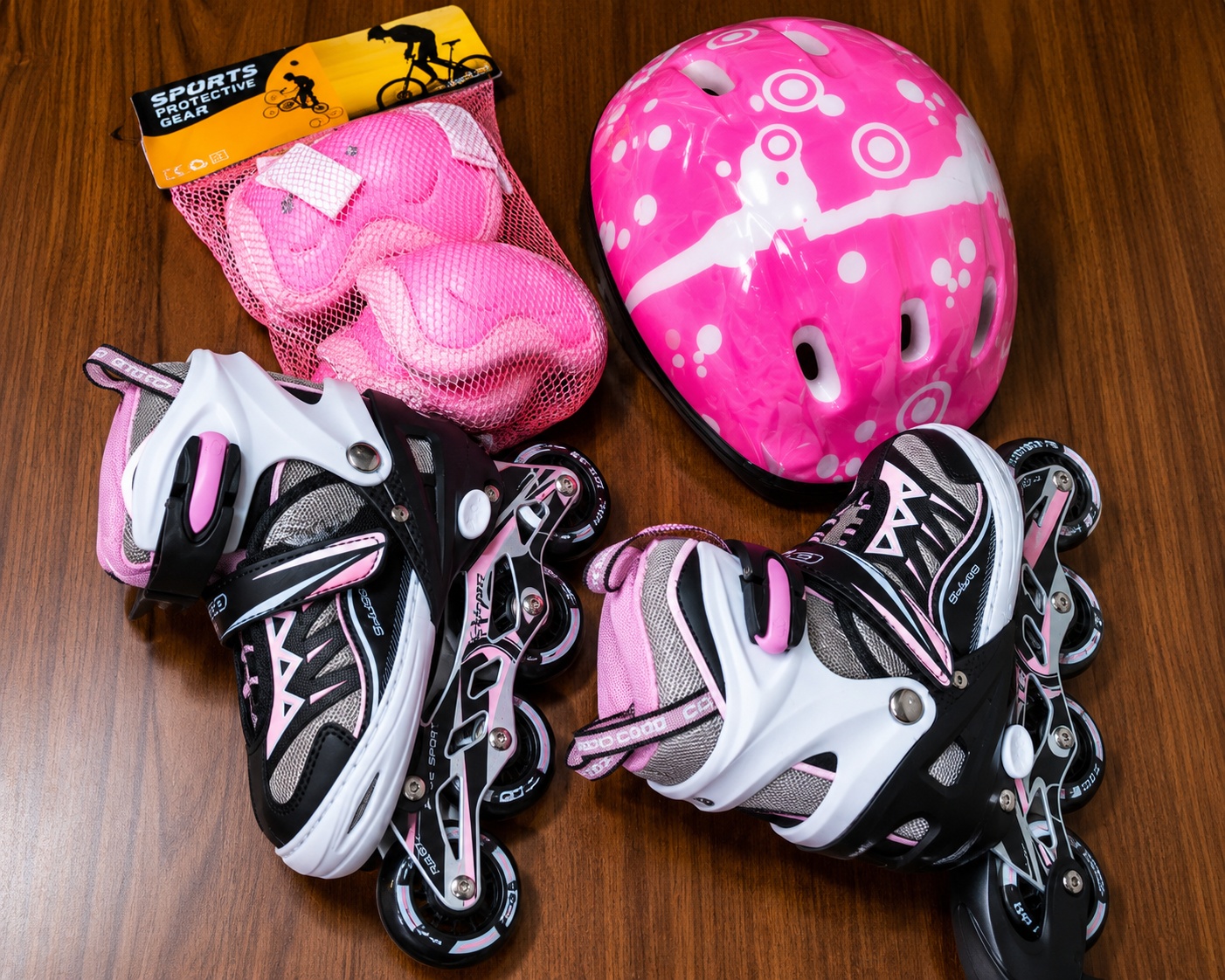 Pink adjustable kids inline roller skates set with matching safety helmet and protective knee, elbow, and wrist pads.