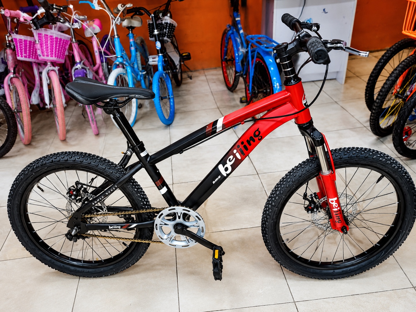 Beijing 20-inch red and black kids mountain bike with front suspension and front and rear mechanical disc brakes.