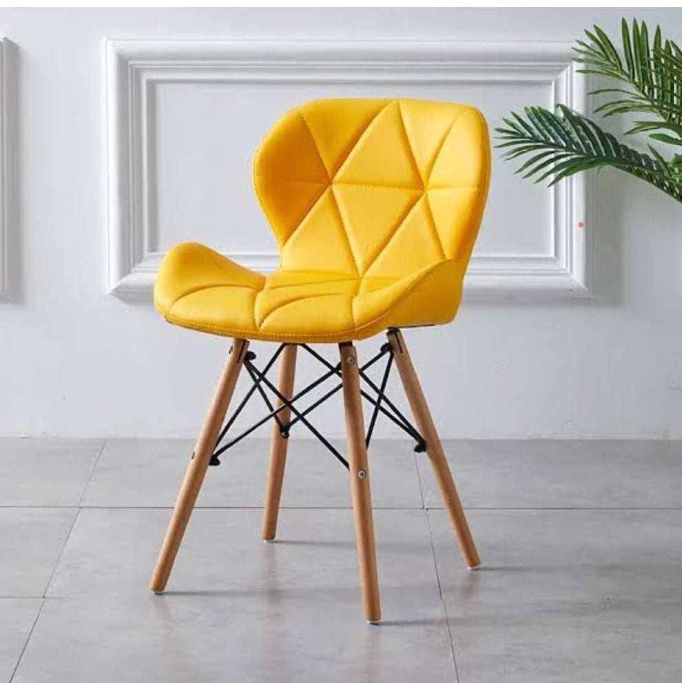 Modern yellow upholstered dining chair with geometric stitched backrest, wooden legs, and reinforced metal support frame.
