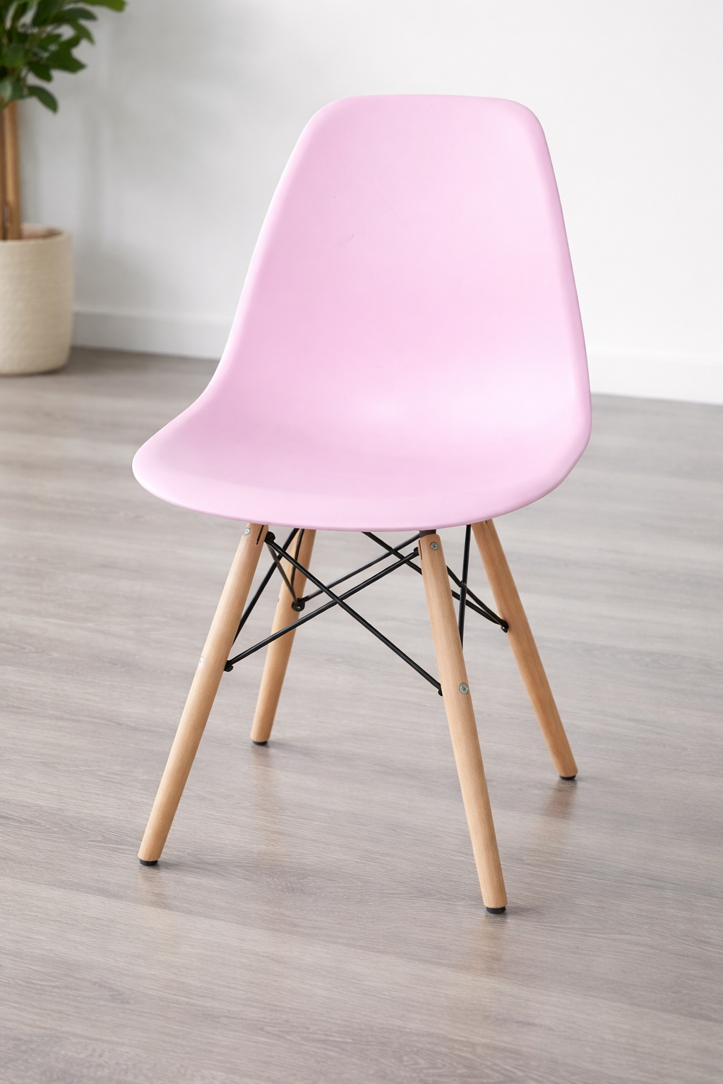 Modern pink dining chair with molded seat, natural wooden legs, and black metal support frame.
