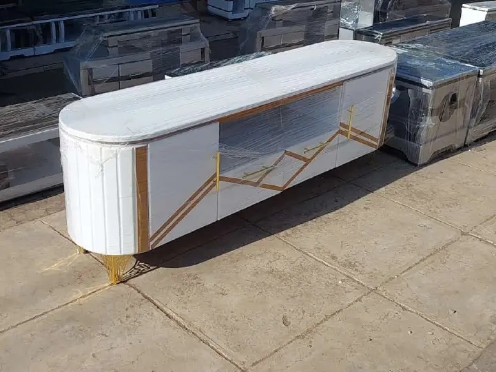 Luxury white TV console cabinet with gold accents, curved side panels, storage compartments, and elevated metal legs.