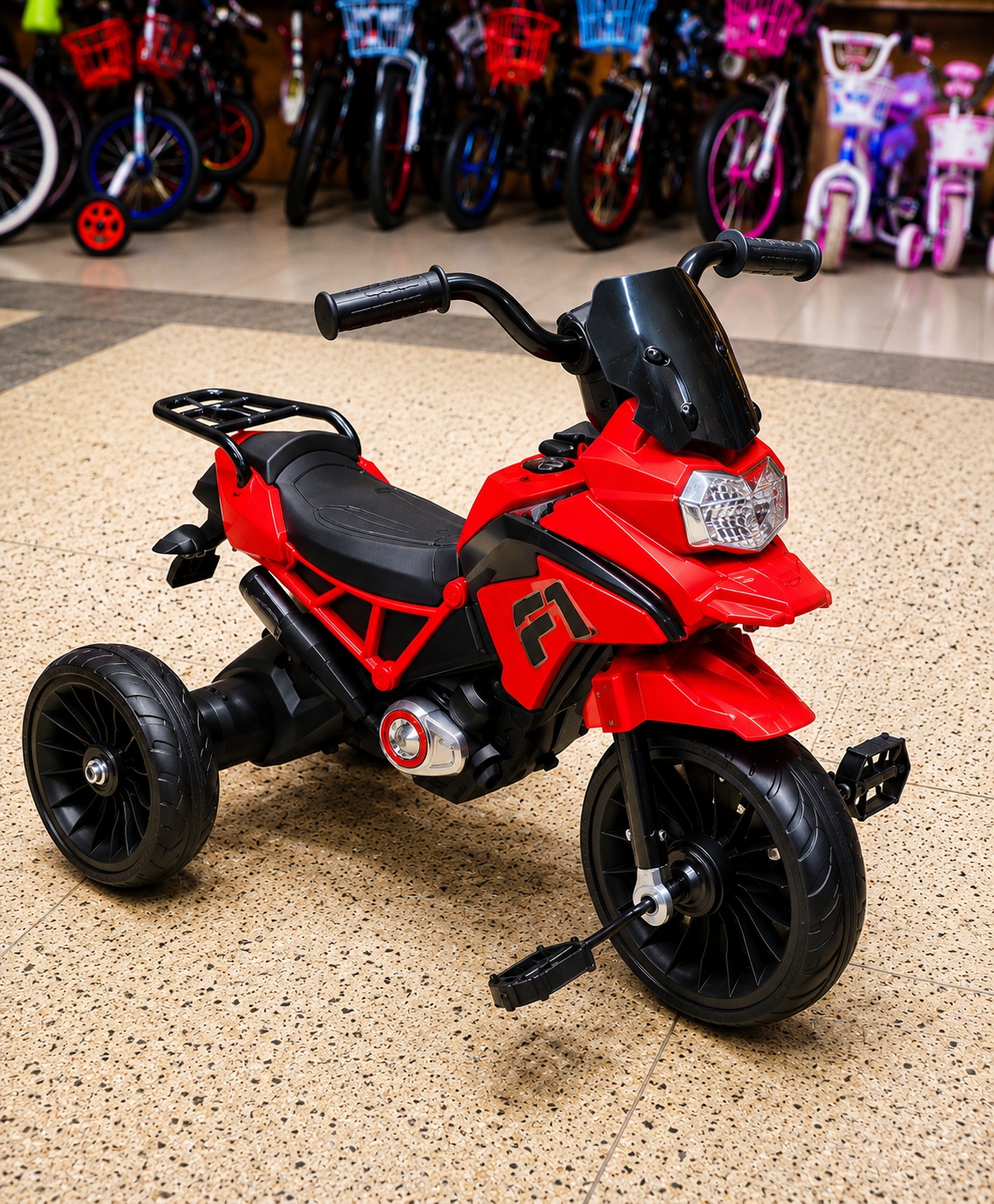 Red kids tricycle with three wide wheels, black seat, handlebars and sporty motorcycle-inspired design
